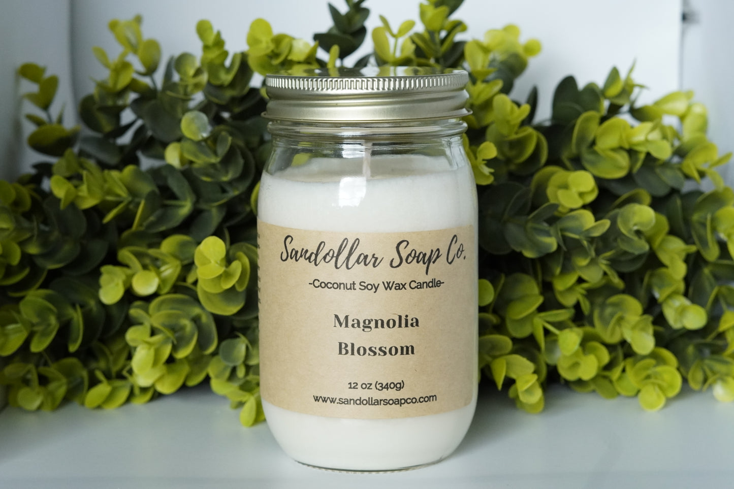 A 12 oz coconut soy wax candle in a mason jar that includes a gold lid. Made with a cotton wick and scented "Magnolia Blossom." Magnolia, rose, orange flower, jasmine, lily come together for this beautiful spring scent.