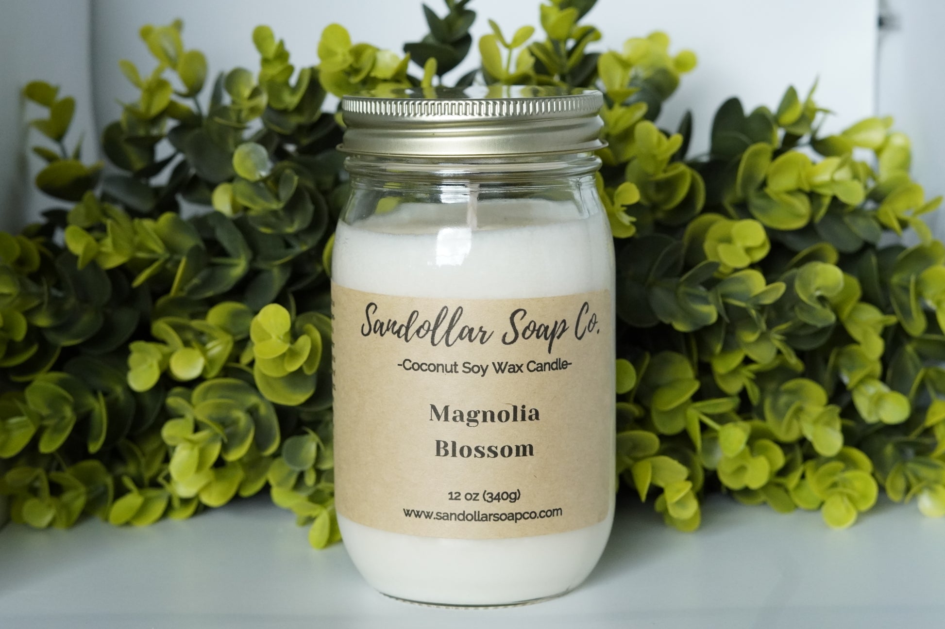 A 12 oz coconut soy wax candle in a mason jar that includes a gold lid. Made with a cotton wick and scented "Magnolia Blossom." Magnolia, rose, orange flower, jasmine, lily come together for this beautiful spring scent.