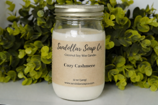 photo of a mason jar candle labeled "cozy cashmere" with greenery in the background