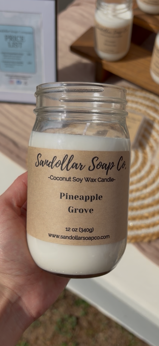 Hand holding a candle labeled 'Pineapple Grove'