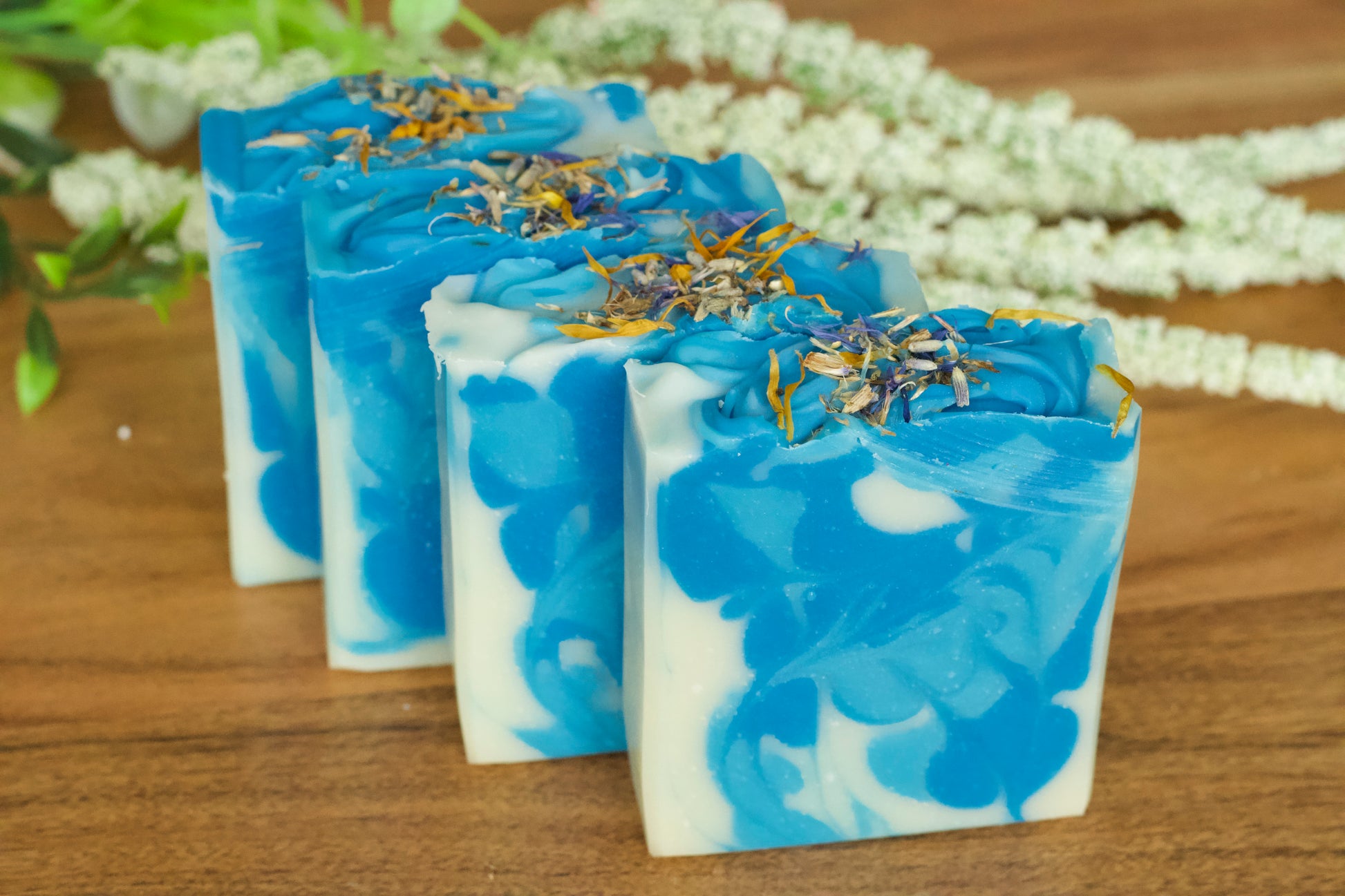 Handmade bar soap with a blue and white marbled pattern, topped with dried flower petals.