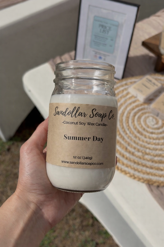 hand holding a mason jar candle labeled "orange blossom" with a blurred background